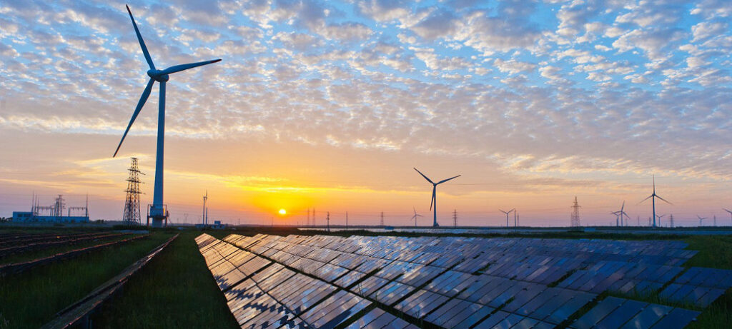Solarpark mit Windrädern im Hintergrund und bei Sonnenuntergang
